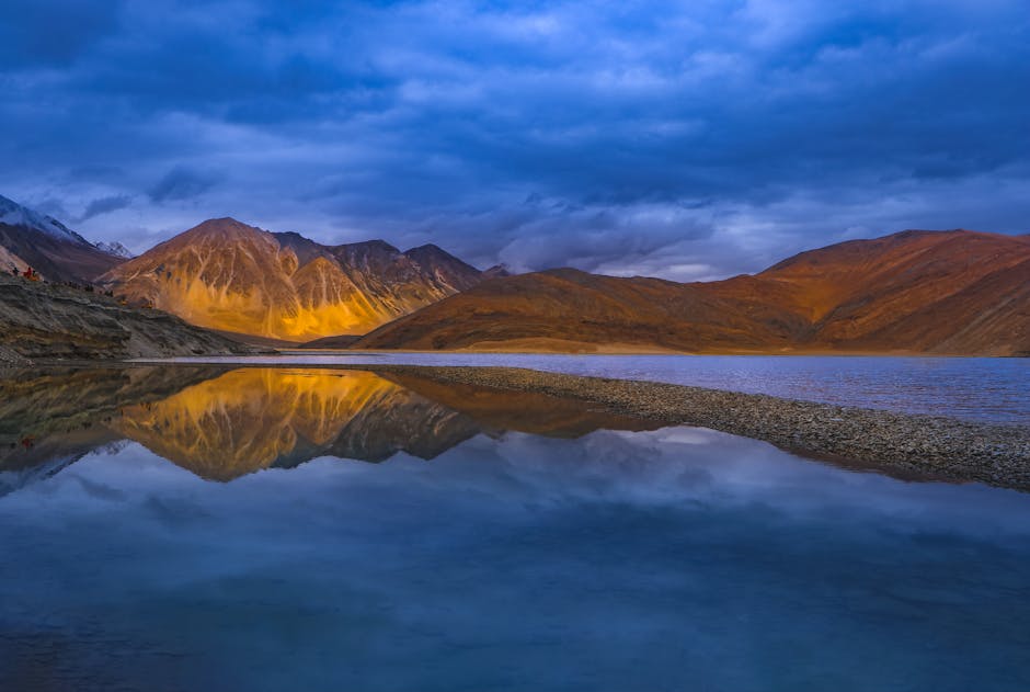 Stunning view of Leh mountains reflected in a tranquil lake at sunset.
