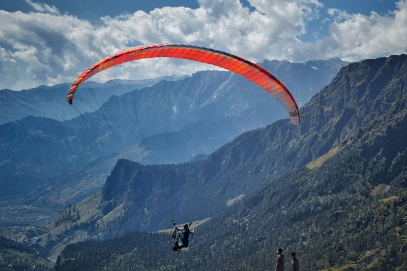 Experience the thrill of paragliding over scenic mountains on a clear day.