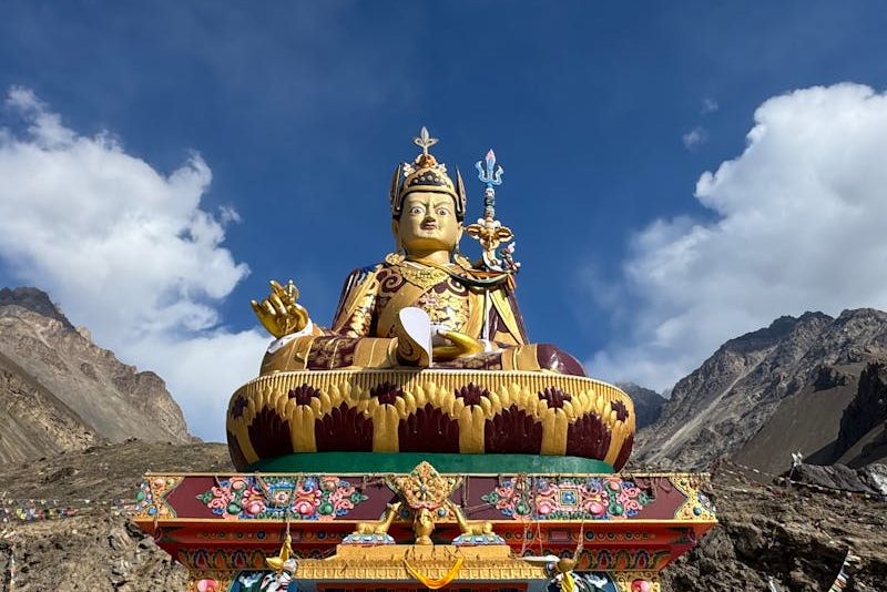 A vibrant statue at Key Monastery surrounded by mountains under a clear blue sky in Spiti Valley, India.